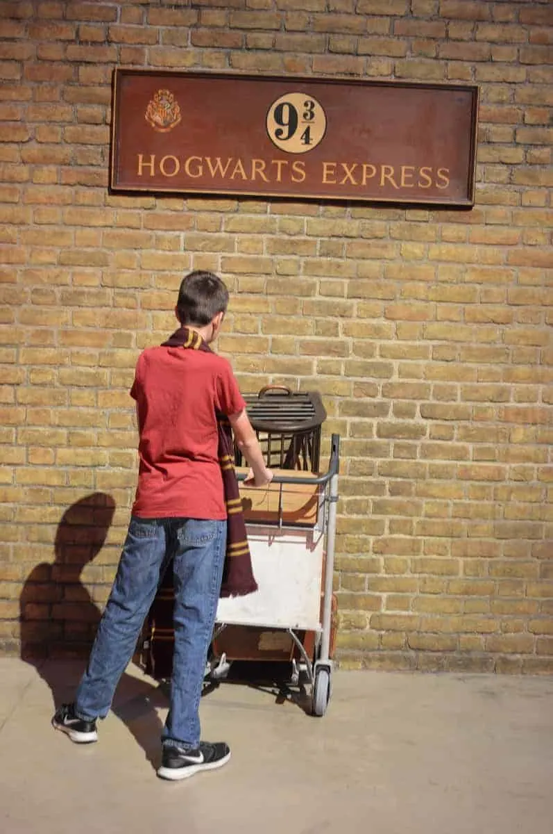 Run through the wall at Platform 9 3/4 at the Harry Potter theme park in London